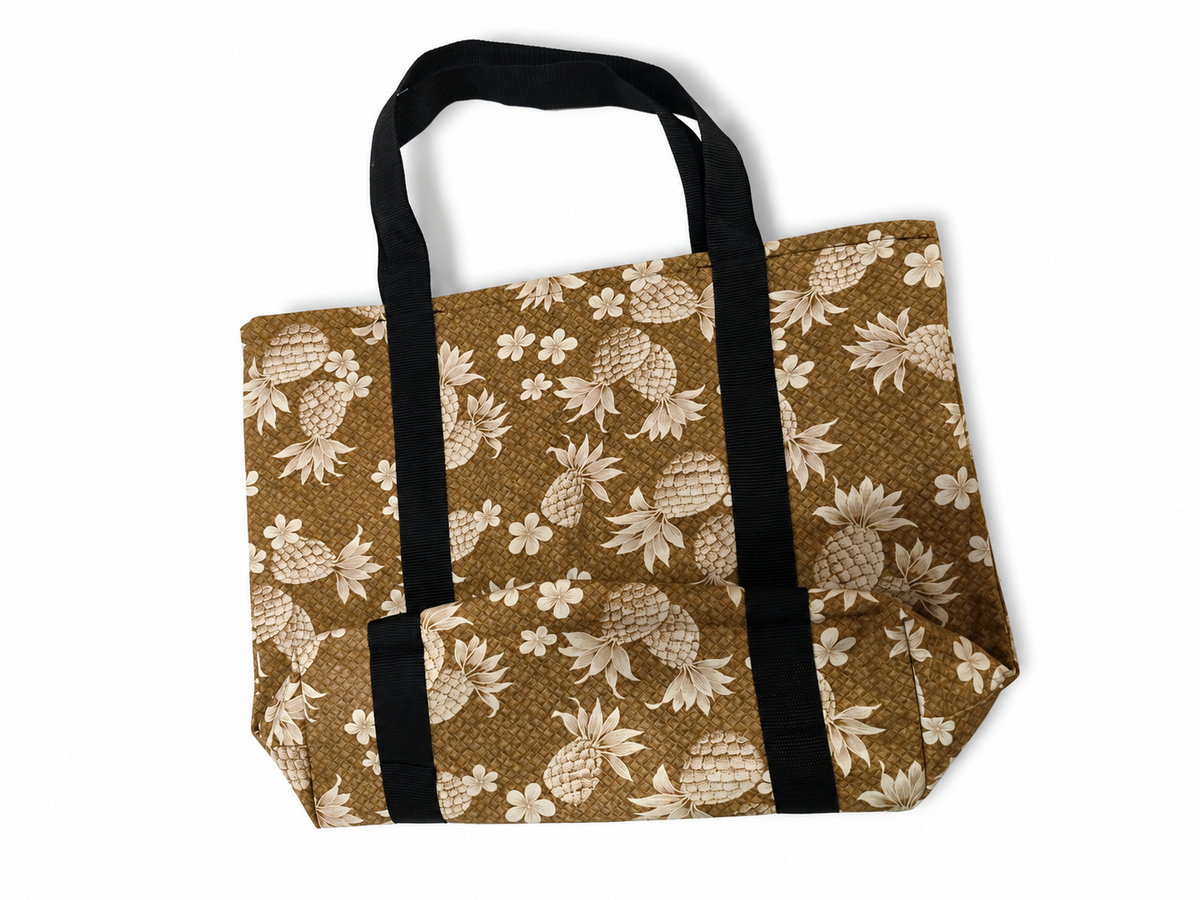 A brown canvas tote bag with a cream pineapple and floral print, featuring two black webbed handles, shown on a plain white background.