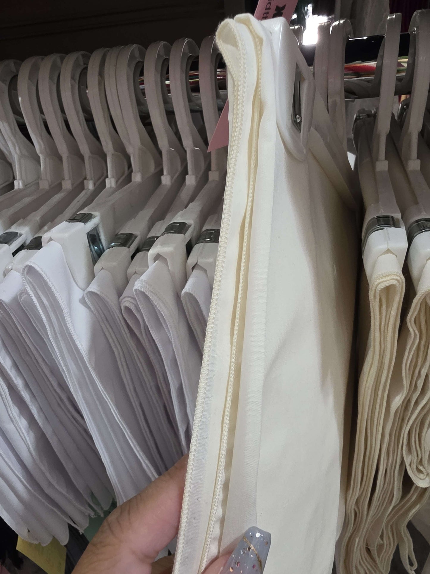 White fabric on a hanger with a blurred background of similar items.