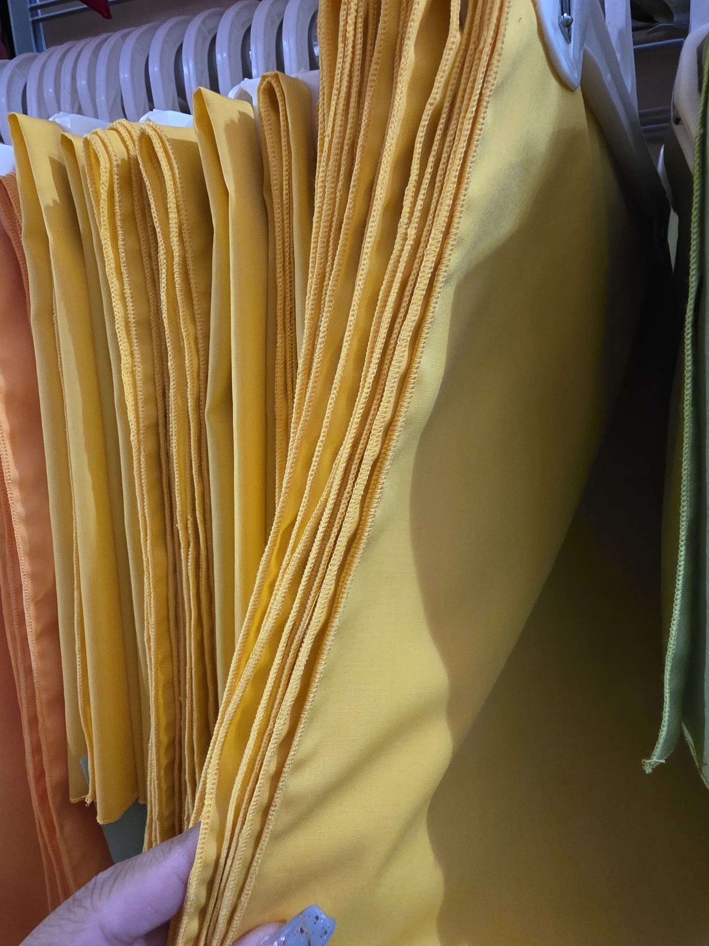 Close-up of yellow fabric on a rack with a hand holding it.