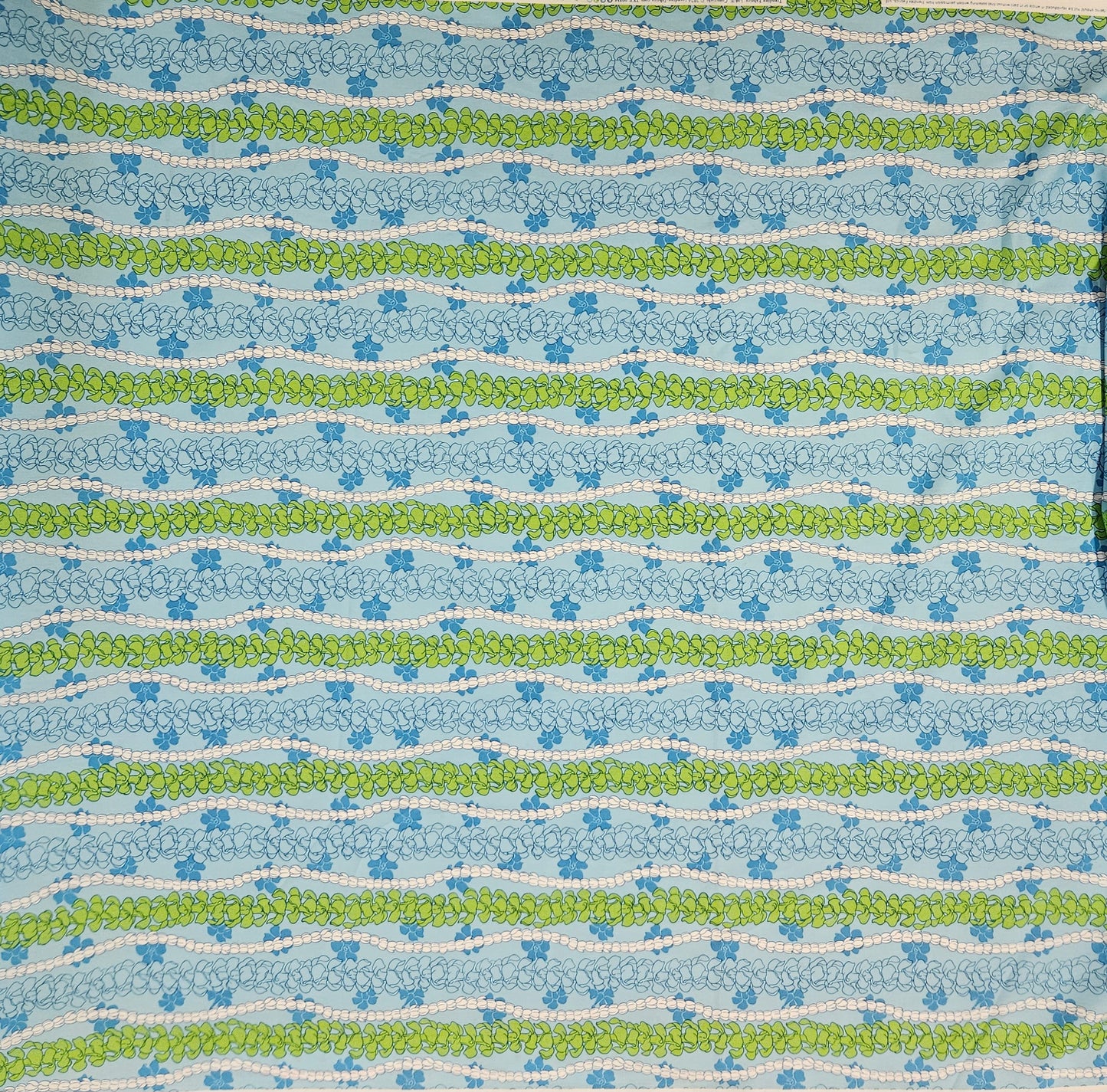 Patterned fabric with blue, green, and white floral stripes on a blue background