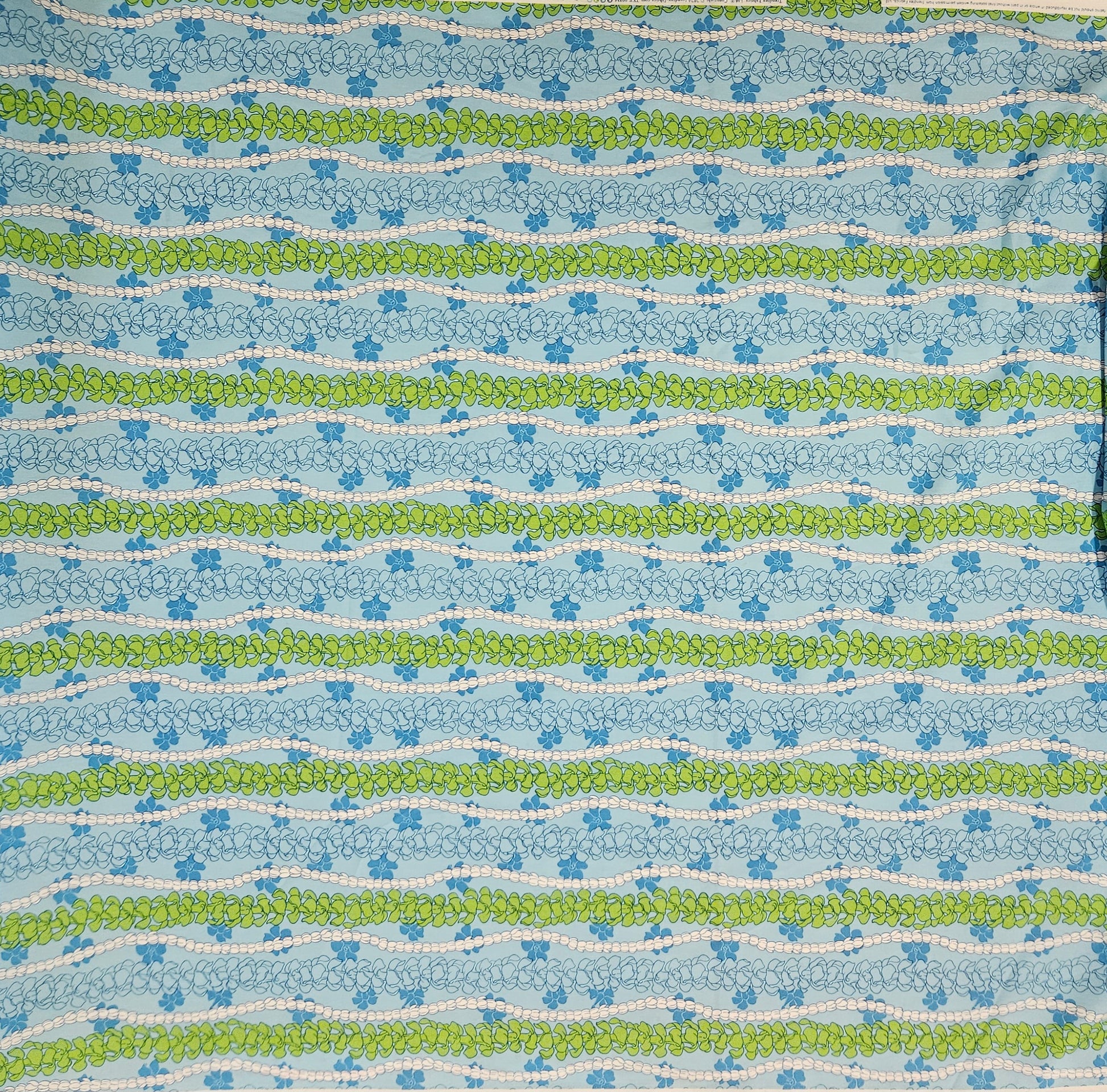 Patterned fabric with blue, green, and white floral stripes on a blue background