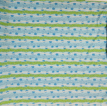 Patterned fabric with blue, green, and white floral stripes on a blue background