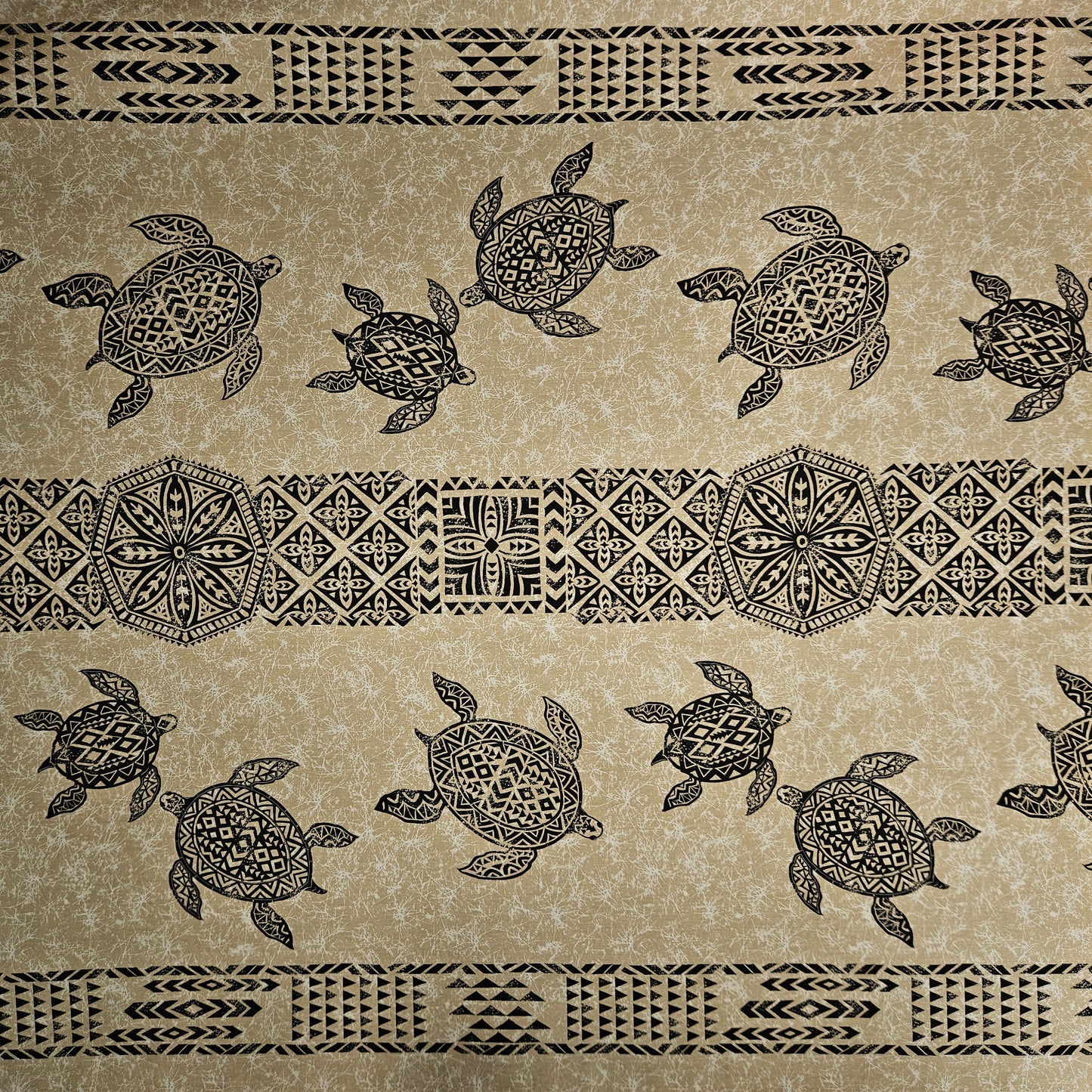 Patterned fabric with turtles and tribal designs on a beige background